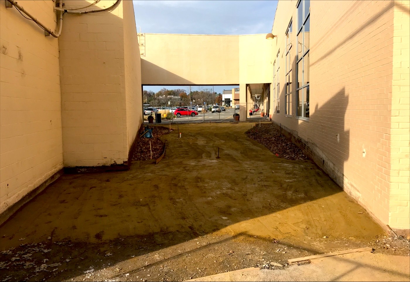 Bare graded dirt corridor between two commercial buildings before paving