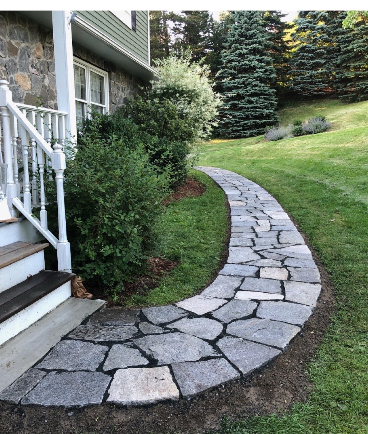 Curving flagstone walkway leading from a front porch through a lawn