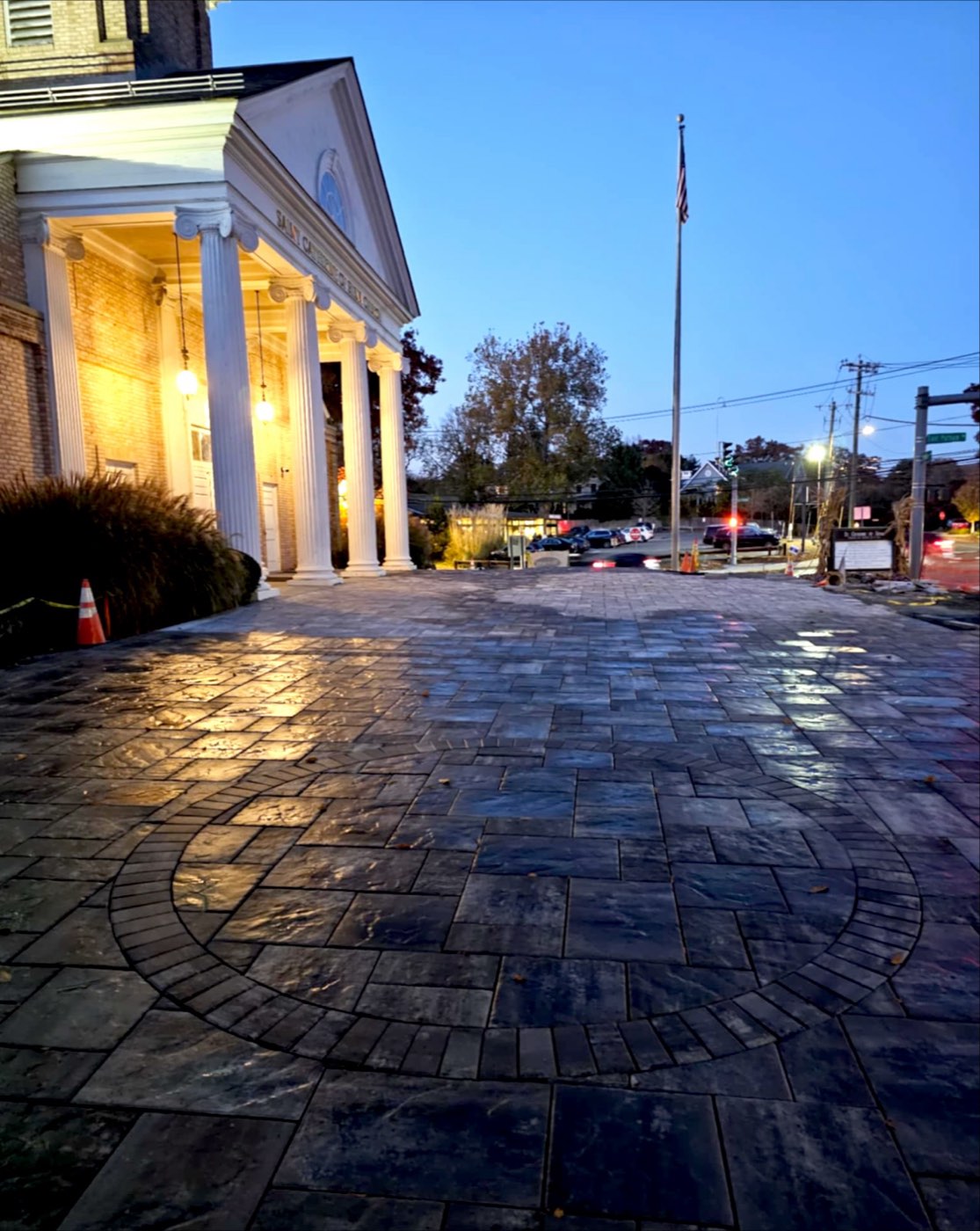 Paver plaza with a circular inlay in front of a columned civic building at twilight